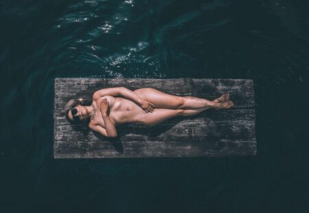 Frau liegt auf einem Holzfloß im dunklen Wasser, senkrecht von oben fotografiert – Drohnenfotografie vom Fotograf aus Gera