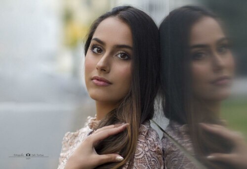 Junge Frau im Spitzenkleid lehnt an einer Glasfassade, daneben ihr Spiegelbild – Portraitfotografie am Theater in Gera